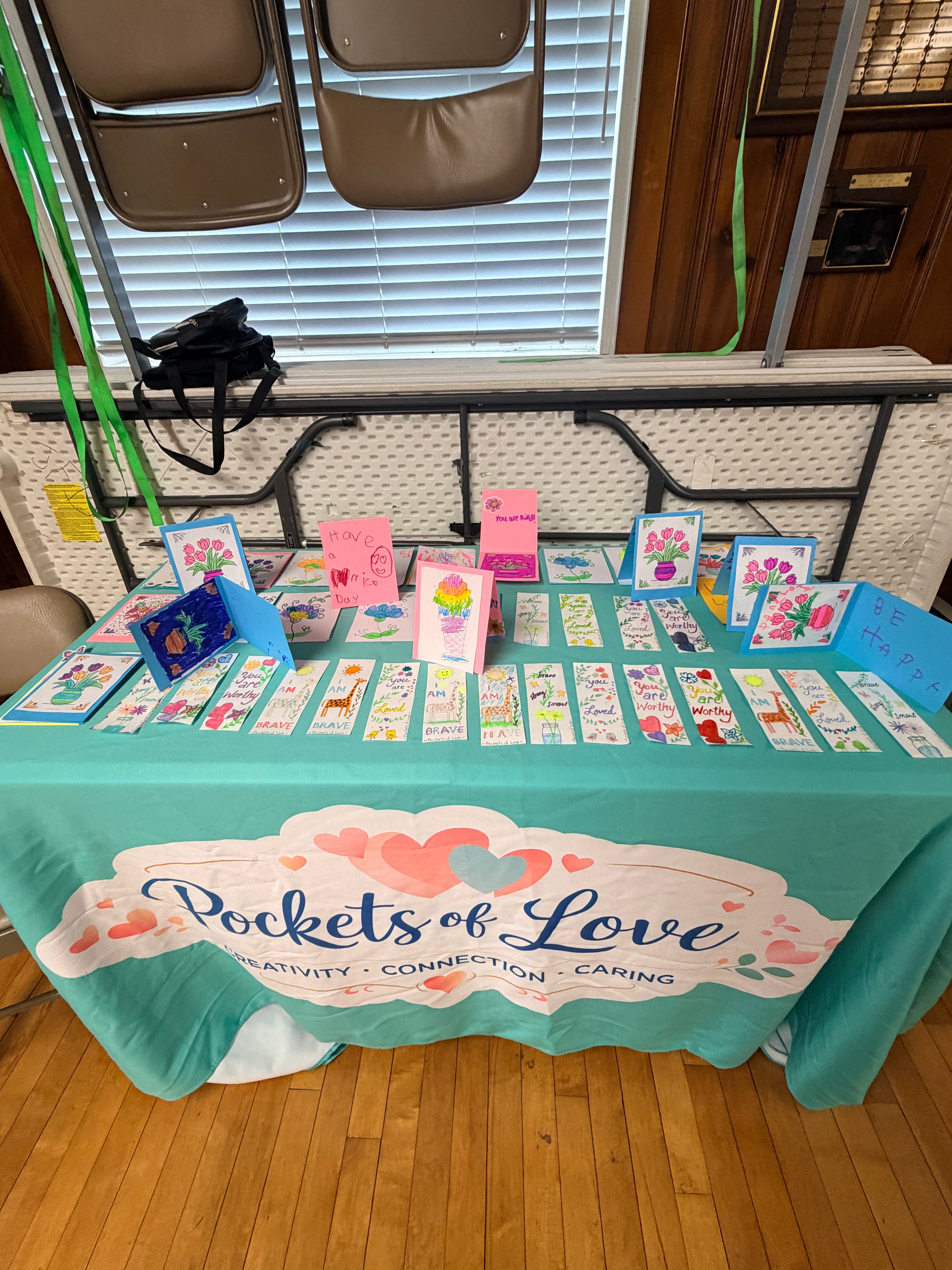 Pockets of Love teal display booth with colorful art cards